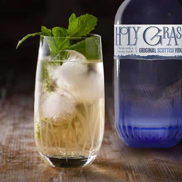 Bottle of Holy Grass Vodka and perfect serve in a tall glass with ice and garnish