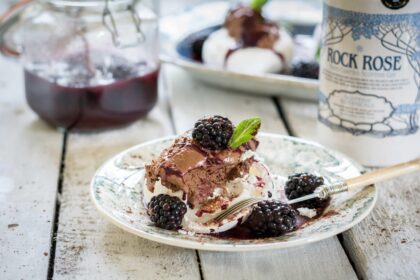 Bottle of Rock Rose Gin and slice of Choc pavlova served in a plate and topped with blackberries