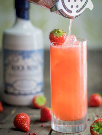 Bottle of Rock Rose Gin and The Pepperman Cocktail served in a tall glass and garnished with a strawberry