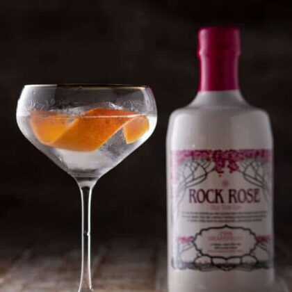 Bottle of Pink Grapefruit Old Tom Gin and Perfect Serve in a coupe glass