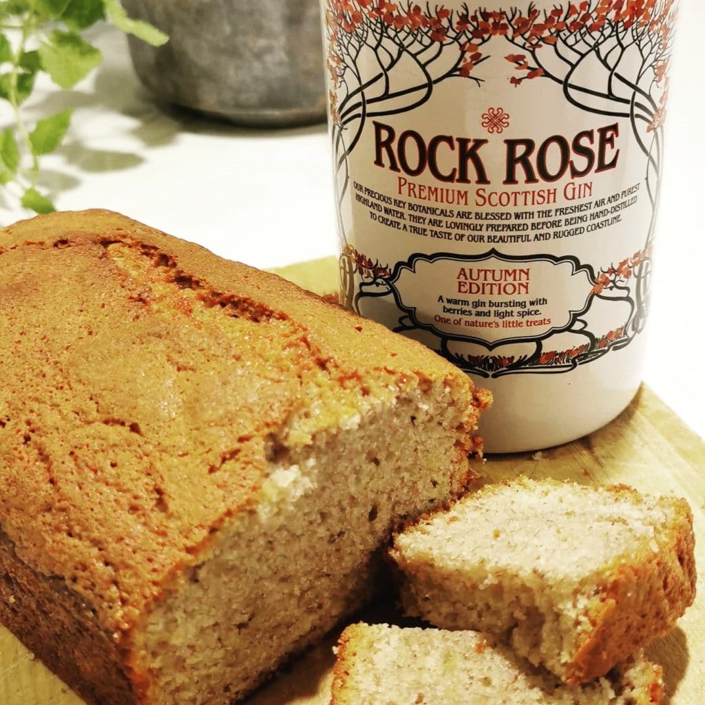 Bottle of Rock Rose Gin Autumn edition and slices of Autumn Banana Bread on a wooden board