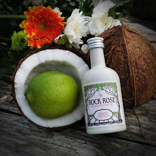 Half a coconut with a lime inside next to a miniature bottle of Rock Rose Gin Spring edition
