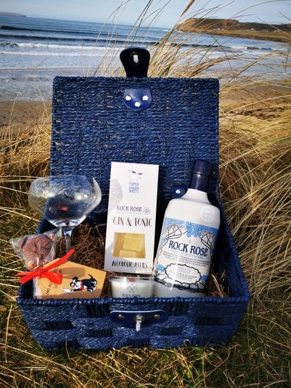 Picture of our "All Things Rock Rose" hamper including a bottle of Rock Rose Gin Original Edition, a branded glass, a candle, and a Chocolate Lollipup, Gin & Toni jellies
