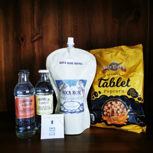Content of the Refill Rewards Club box for April 2022 including Rock Rose Gin pouch, tonic waters, tablet popcorn and an envelop with wildflowers seeds
