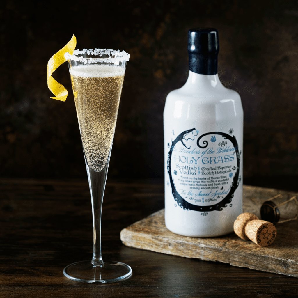 Bottle of Holy Grass Vodka and Platinum Jubilee Fizz cocktail served in a flute decorated with sugar on the rim, and garnished with a twist of lemon