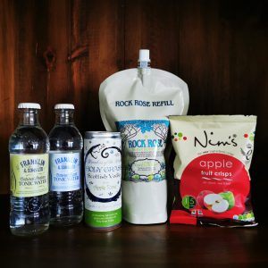 Content of the Refill Rewards Club box for May 2022 including Rock Rose Gin pouch with tonic waters, holy grass vodka with apple tonic can, apple fruit crisps