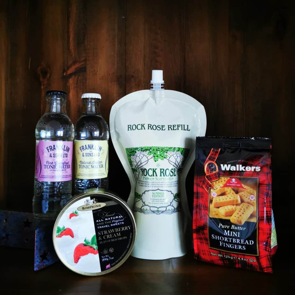 Content of the Refill Rewards Club box for July 2022 including Rock Rose Gin Pouch, tonic waters, Walkers mini shortbread fingers and Strawberry and cream sweeties