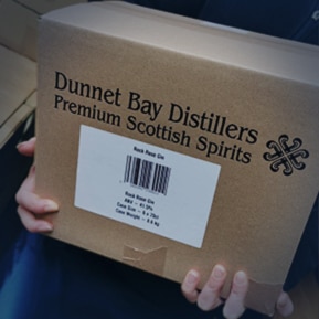 Hand carrying a Dunnet Bay Distillers cardboard box to be delivered