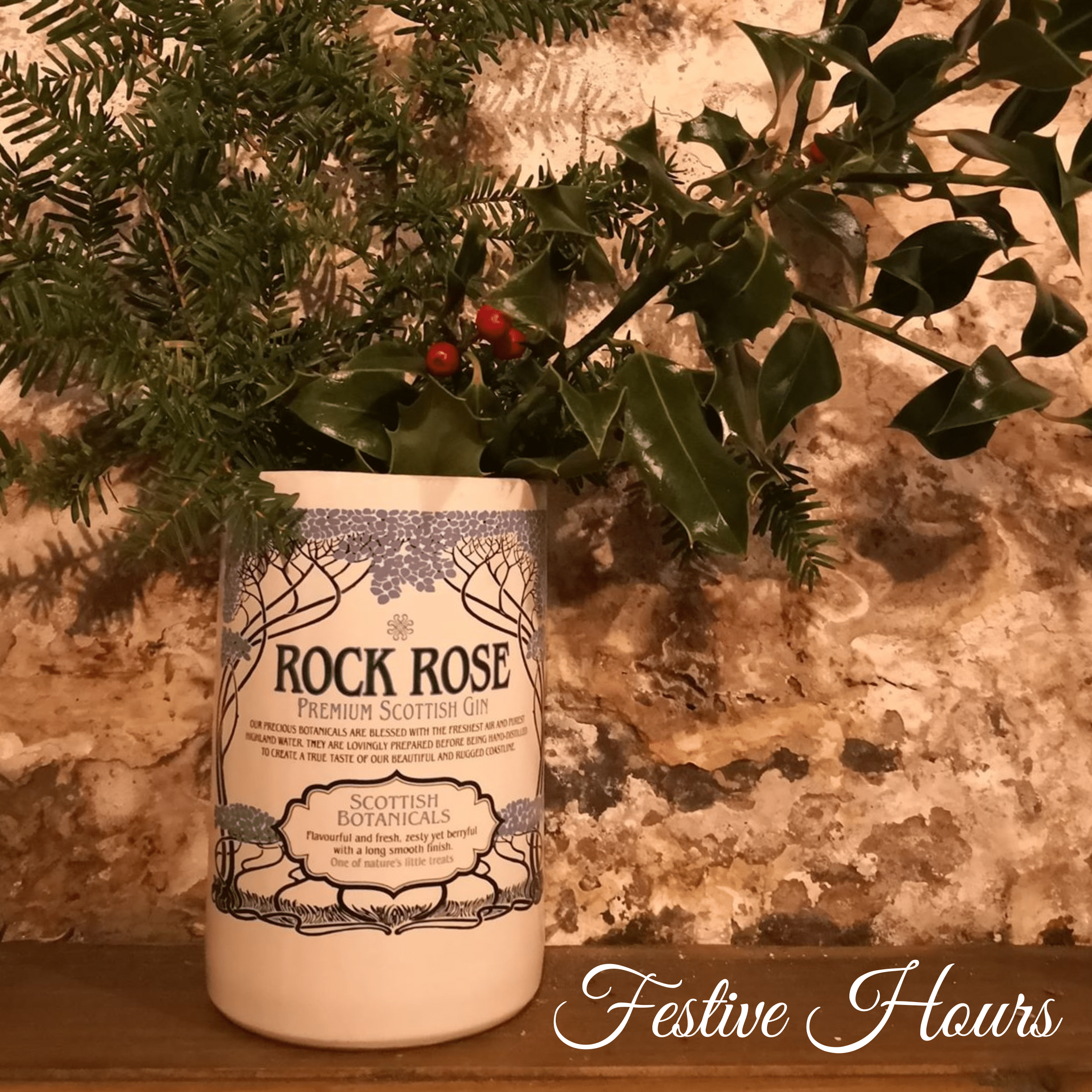 Festive picture with a Rock Rose Gin bottle cut horizontally to make a flower pot and filled with pine tree and holly branches