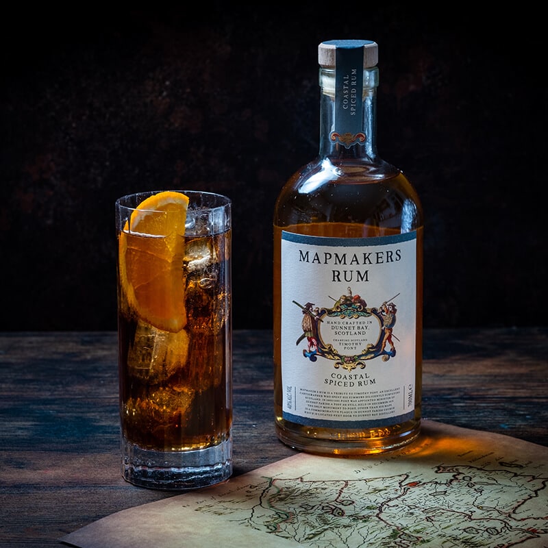 Mapmakers Rum - Coastal Spiced bottle and glass with perfect serve on a table with map